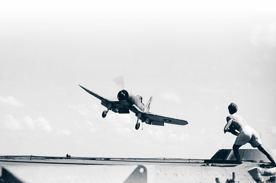 Demonstrating the curved approach needed for deck landings in the F4U, this FAA Corsair JT358, landing on HMS Illustrious in the Indian Ocean in May 1944, still has bank applied as the Deck Landing Control Officer signals the “cut” with his bats. (Photo author’s collection)