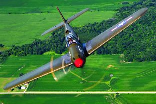 The Central Texas Wing’s P-39Q “Old Crow” with the unit’s chief pilot Craig Hutain at the controls closes up tight on the camera aircraft over the farm fields near Oshkosh, Wisconsin last July during AirVenture 2022.