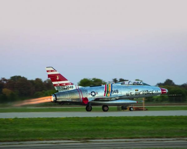 Dean Cutshall goes to full takeoff power to wow the crowd in his ultra-rare, two-place F-100 Super Sabre. Cutshall has flown a number of Vietnam Veterans from the Super Saber Society, who flew it in active service during the Vietnam War. (EAA photo by Andrew Zaback)