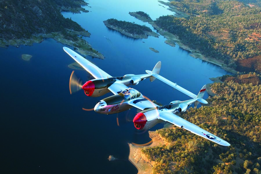 Lockheed P-38H “Honey Bunny” roars over the California landscape with the incomparable Steve Hinton at the controls. This is the only airworthy Lightning with fully functioning original turbo chargers and is now owned by Allied Fighters of Chino, California. Later during WW II, P-38s were flown in both theaters sans OD paint. (Photo by Paul Bowen)