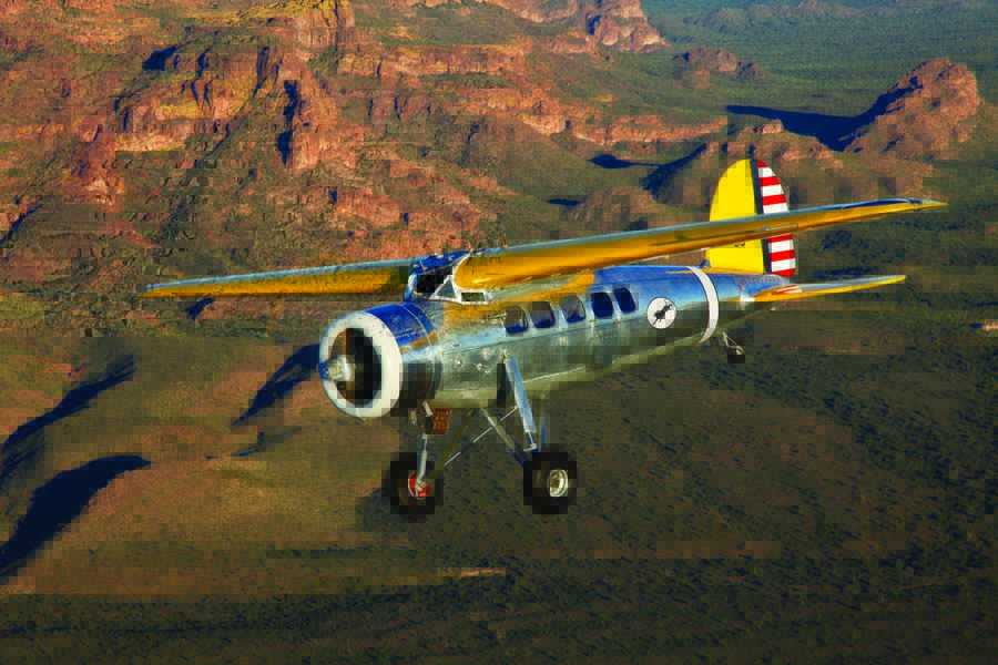 This beautiful and rare DL-1 Lockheed Vega piloted by John Magoffin is framed against the sunlit red rocks high above the Arizona Desert. When Detroit Aircraft bought controlling interest in Lockheed, they designed an aluminum fuselage that followed the lines and function of the original wooden fuselage almost exactly. The current home of this aircraft is the Commemorative Air Force Museum at Falcon Field in Mesa, Arizona.