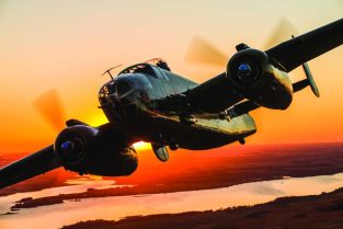 Fagen Fighters B-25J-30-NC “Paper Doll” soars over the Minnesota landscape silhouetted by the late day sun. This aircraft flew with the 447th Bomber Squadron stationed at Solenzara, Corsica during WW II. (Photo by Paul Bowen)